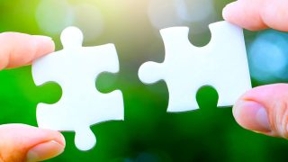 two hands person trying to connect couple Jigsaw paper white puzzle piece